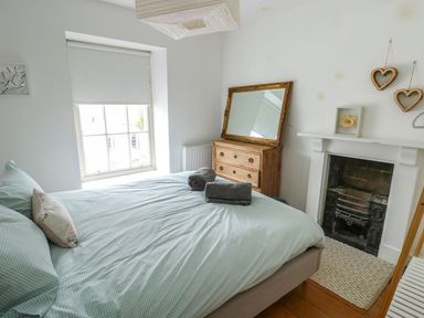 A bedroom with a bed and dresser at Tri Raglan Mawr in Beaumaris