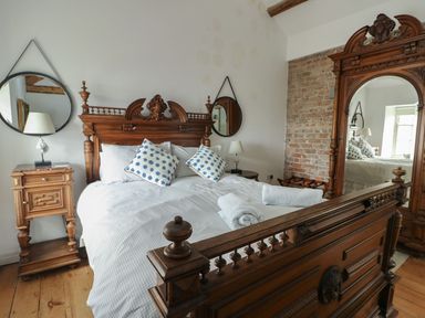 A bedroom with a bed and nightstand at Tri Raglan Mawr Beaumaris