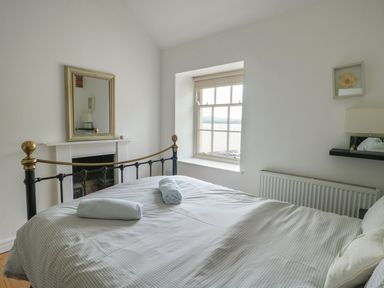 A bedroom with a bed and window at Tri Raglan Mawr in Beaumaris