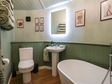 A bathroom with a toilet, sink, bathtub, and wall art at Unit 1 in Ipswich