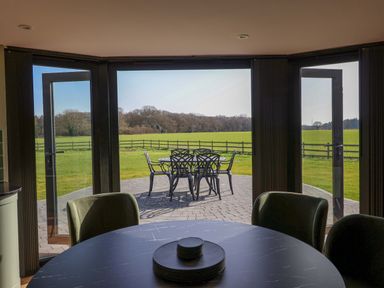 A dining room with doors leading to an outdoor seating area at The Corn Silo in Ipswich