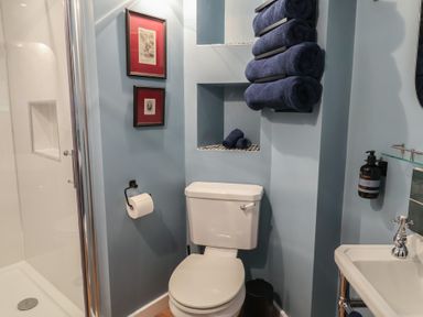 A bathroom with a toilet, towels on shelf, and a sink at Unit 2 Ipswich