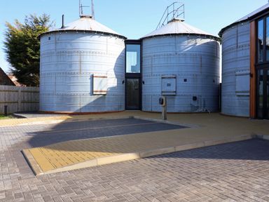 An outdoor area with grain silos and a paved entrance at The Barley Silo in Ipswich