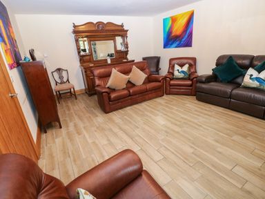 A living room with brown sofas and an ornate mirror at Ty-Gan Dderwen in Llangennech, Llanelli