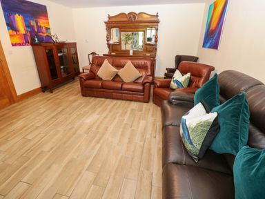 A living room with a sofa and an armchair at Ty-Gan Dderwen Llangennech, Llanelli