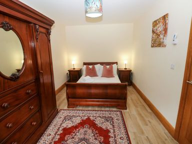 A bedroom with a bed and wardrobe at Ty-Gan Dderwen in Llangennech, Llanelli