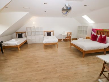 A bedroom with three beds and a shelf unit at Ty-Gan Dderwen in Llangennech, Llanelli