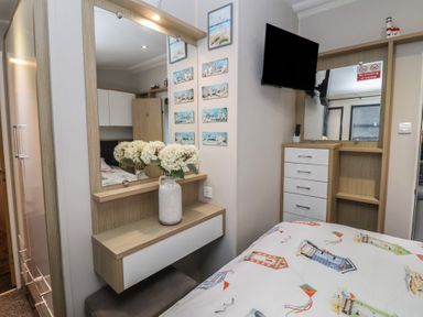 A bedroom with a bed, mirror, and television at Offspray Court 1, Scratby