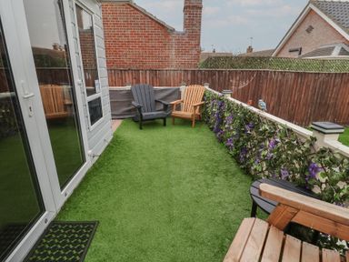 A garden with chairs and flowers at Offspray Court 1 Scratby