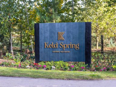 A sign for Keld Spring Lodge Retreat in a garden setting