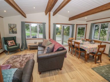 A living room with a sofa and dining area at Oak Lodge in Admaston near Abbots Bromley