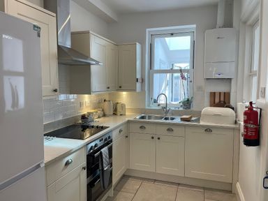 A kitchen with cabinets and appliances at Seahorse Cottage in Weymouth