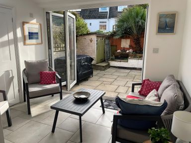 A sunroom with seating and a view of the garden at Seahorse Cottage in Weymouth