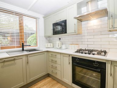 A kitchen with a sink, stove, microwave, and kettle at Terabitha Lodge in Troutbeck