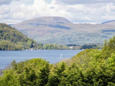 A scenic view of a lake surrounded by trees and mountains at Terabitha Lodge in Troutbeck