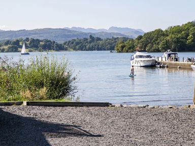 A lake scene with boats and a person on a paddle board at Terabitha Lodge Troutbeck
