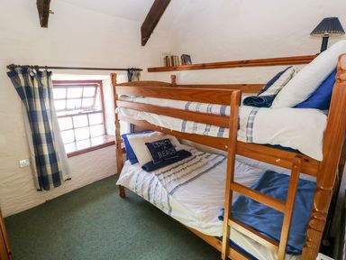 A bedroom with a bunk bed and window at Ty Fferm Newport