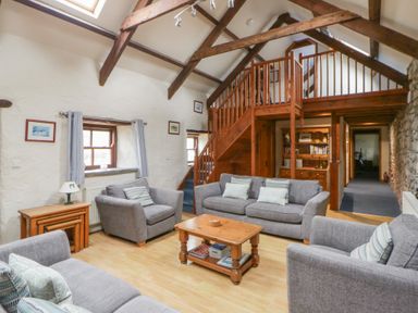 A living room with sofas and a staircase at Ty Felin Newport, Pembrokeshire
