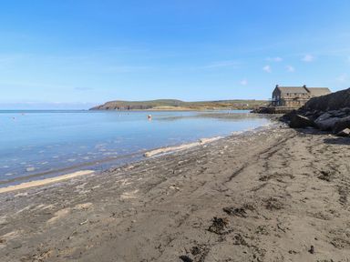 A beach with water and a house in the background at Ty Gwartheg Newport