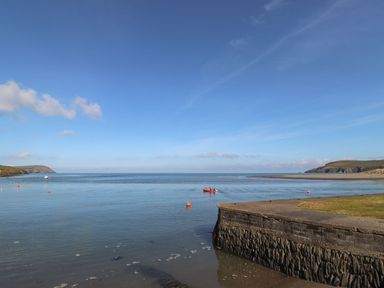 A water scene with a boat and rocky bank at Ty Gwartheg Newport