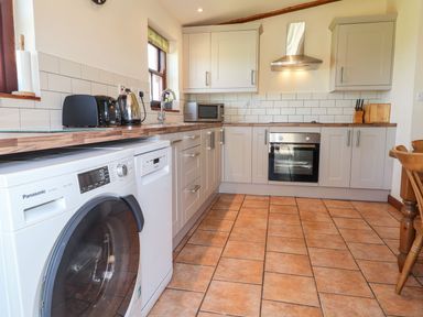 A kitchen with a washing machine and appliances at Ty Cariad in Newport