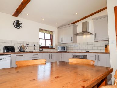 A kitchen with appliances and wooden table at Ty Cariad in Newport
