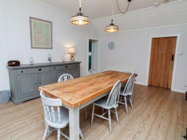 A dining room with a wooden table and chairs at Braeburn in Bamburgh