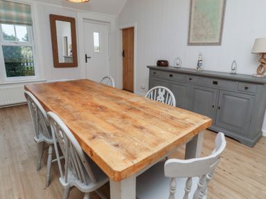 A dining room with a wooden table and chairs at Braeburn in Bamburgh