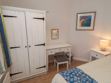 A bedroom with a wardrobe and desk at Braeburn in Bamburgh