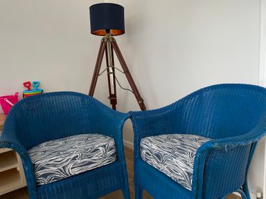 Two blue chairs and a tripod lamp in a living room at Braeburn in Bamburgh