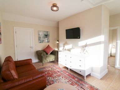 A living room with a sofa, armchair, and television at Duck Cottage