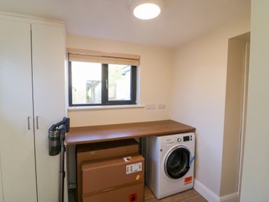 A laundry room with a washing machine and a worktop at Duck Cottage