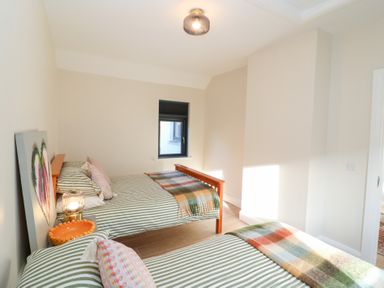 A bedroom with two beds and a window at Duck Cottage
