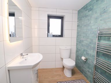 A bathroom with a sink, toilet, and towel rack at Duck Cottage