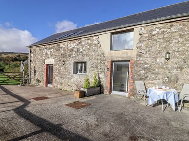 An outdoor area with a stone building and patio furniture at Dairy Cottage Bullhornstone near South Brent