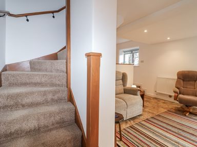 A living room with a staircase and a recliner chair at Dairy Cottage Bullhornstone near South Brent