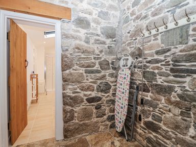 A utility room with an ironing board and hooks at Dairy Cottage Bullhornstone near South Brent
