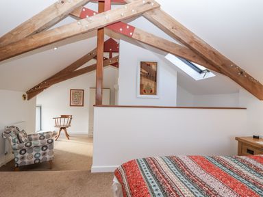 A bedroom with a bed and a chair at Dairy Cottage in Bullhornstone near South Brent