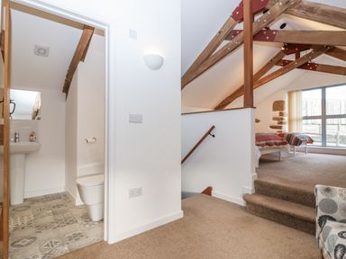 A bedroom with a staircase and bathroom access at Dairy Cottage Bullhornstone near South Brent