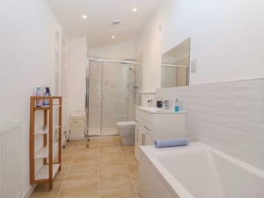 A bathroom with a bathtub, shower, sink, and toilet at Dairy Cottage Bullhornstone near South Brent