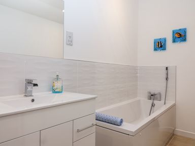 A bathroom with a sink, bath, and mirror at Dairy Cottage in Bullhornstone near South Brent