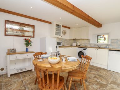 A kitchen with a round table and chairs at Swallow Cottage in Bullhornstone near South Brent