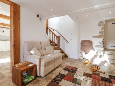 A living room with a sofa and armchair at Swallow Cottage in Bullhornstone near South Brent