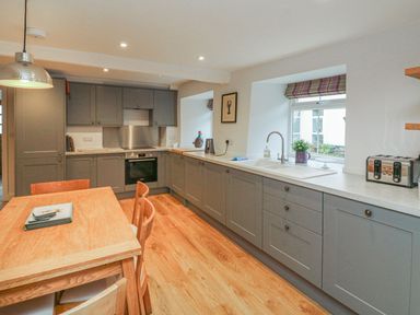 A kitchen with cabinets, table, and chairs at The Old Workshop in 