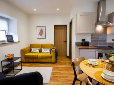 A living room with a yellow couch and dining table at Oakwood Apartment in Llanrwst
