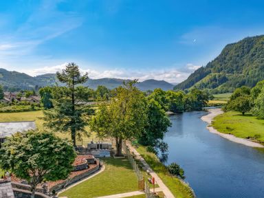 A view of a river and surrounding trees at Beech Cottages in Llanrwst