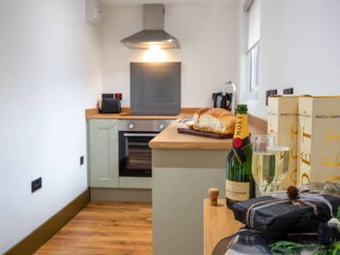 A kitchen with a bottle of champagne and bread at Beech Cottages in Llanrwst