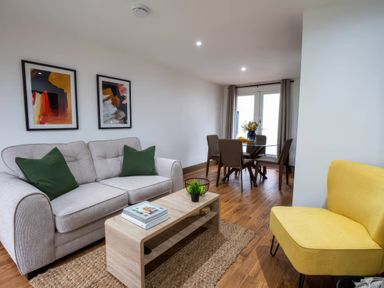 A living room with a sofa a coffee table and a dining area at Beech Cottages Llanrwst