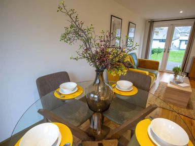 A dining room with a table set and a sofa at Silver Birch Cottage in Llanrwst