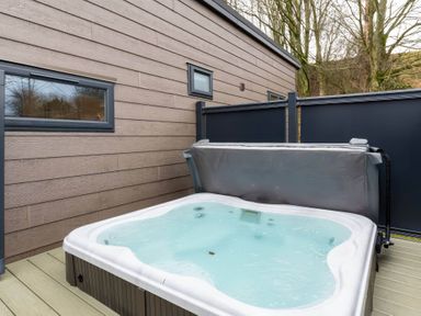 A hot tub on a deck next to an exterior wall at The Falls in Leyburn